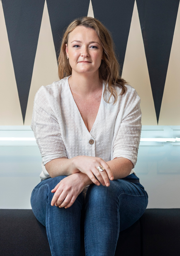 lauren rogers graphic designer sitting on a couch in jeans